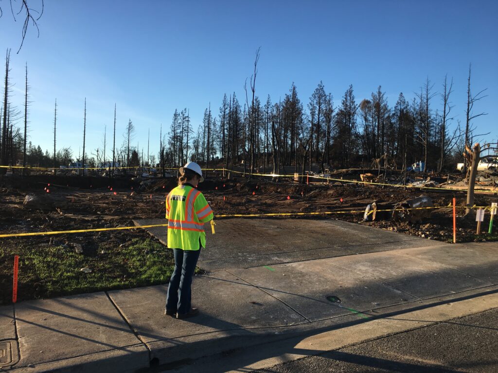 A field worker surveys fire damage in California.