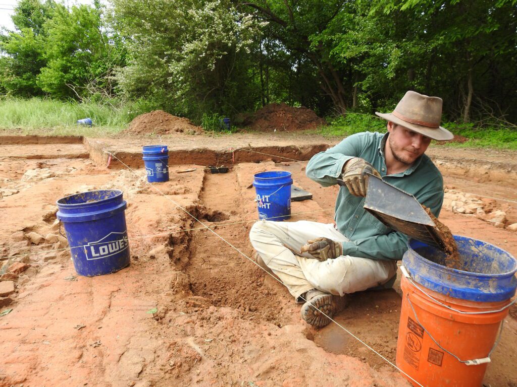 A Chronicle Heritage archaeologist digs out a channel at a brick kiln site in northern Mississippi.