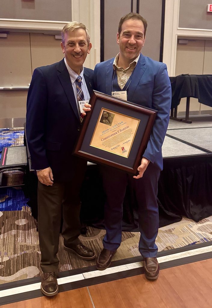 Dr. Christopher Barton (right) poses with the 2025 John L. Cotter Award at a ceremony hosted by the Society for Historical Archaeology.