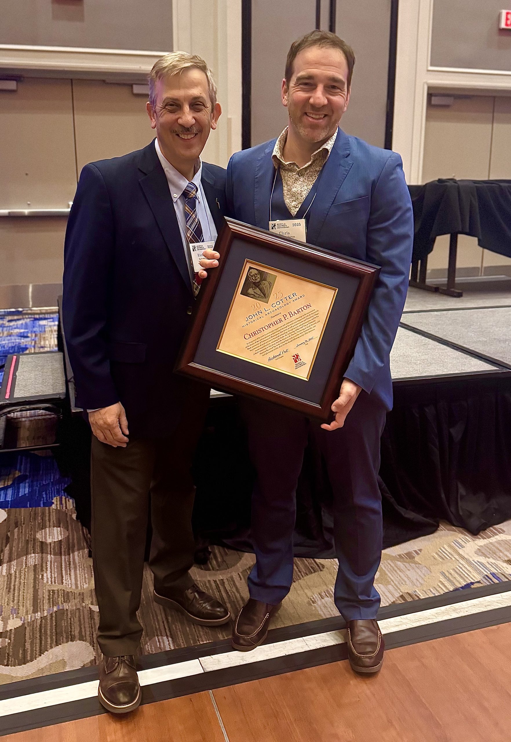 Dr. Christopher Barton (right) poses with the 2025 John L. Cotter Award at a ceremony hosted by the Society for Historical Archaeology.