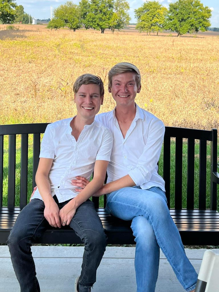 Evan McCurdy (right) poses with his husband at a park.